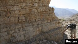 A researcher studies rocks in the United Arab Emirates that were on the seafloor at the time and contained a detailed record of the changing ocean conditions at the end of the Permian Period in this undated handout image released on April 9, 2015.