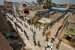 People stand on the lines by maintaining safe distance as they wait to receive free food being distributed by Central Reserve Police Force during a 21-day nationwide lockdown to slow the spreading of coronavirus in Chennai, India, April 1, 2020.