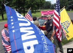 A group of Trump supporters hold flags as they gather near signs on the car of a Trump protester as the two protesting groups met not far from Trump National golf course, where President Donald Trump is attending the Women's US Open tournament, July 15, 2