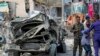 Security forces stand near the wreckage of an official vehicle that was destroyed in a bomb attack in the capital Mogadishu, Somalia Saturday, June 15, 2019. 