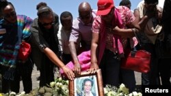 United Nations workers hold a framed photograph as they mourn their colleagues during a commemoration ceremony for the victims at the scene of the Ethiopian Airlines Flight ET 302 plane crash, near the town of Bishoftu, near Addis Ababa, Ethiopia, March 15, 2019. 