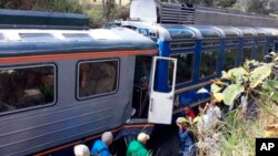 In this photo provided by the government news agency Andina, passengers observe two trains after they collided in Cuzco, Peru, July 31, 2018. The two trains collided near the ancient Incan citadel of Machu Picchu, a prized archaeological site in Peru visited by thousands of tourists each year.
