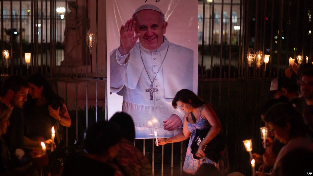 Jemaat meletakkan lilin yang menyala di dekat foto Paus Fransiskus selama acara doa bersama untuk kesehatannya di Buenos Aires pada 7 Maret 2025. (Foto: AFP)