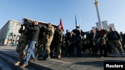 People carry the coffin containing the body of Ukrainian serviceman Volodymyr Andreshkiv, killed while fighting with pro-Russian separatists in eastern Ukraine, during a memorial ceremony at the Independence Square in central Kiev, Ukraine, Dec. 22, 2016.