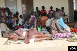 FILE - A young South Sudanese refugee girl shields her face from the scorching sun as she waits in line at Maaji Health Center, Adjumani district, northern Uganda, June 14, 2017. (H. Athumani/VOA)