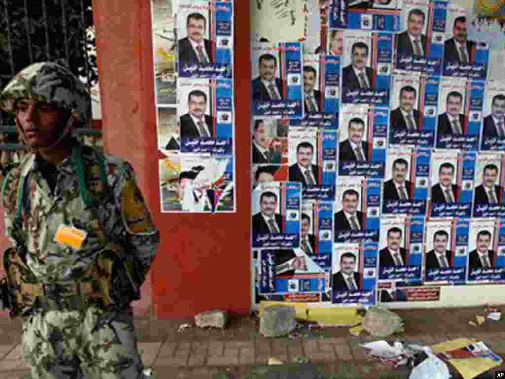 An Egyptian soldier stands next to posters of parliamentary candidates outside a polling center in Assuit, south of Cairo.
