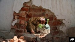 An Indian policeman looks at a hole made in a wall of a police station caused by mortar shell firing allegedly from the Pakistan side of the border, In Arnia sector, about 47 kilometers (30 miles) from Jammu, India, Monday, May 21, 2018.