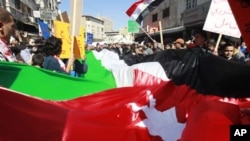 Protesters from Jordanian opposition parties carry a giant national flag while shouting anti-government slogans during a demonstration against what they say are worsening economic conditions, after Friday prayers in Amman, February 18, 2011