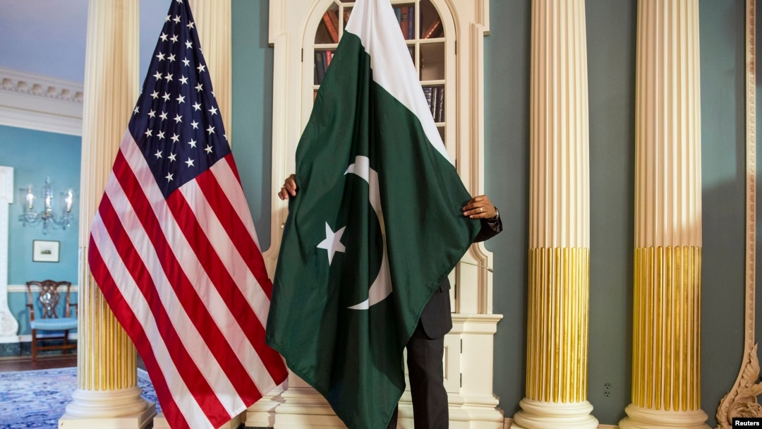 A State Department employee adjusts a Pakistani national flag before a meeting of U.S. and Pakistani officials at the State Department in Washington, Feb. 19, 2015. A U.S. Defense Department delegation is traveling to Pakistan for talks next week. 