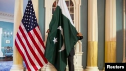 A State Department employee adjusts a Pakistani national flag before a meeting of U.S. and Pakistani officials at the State Department in Washington, Feb. 19, 2015. A U.S. Defense Department delegation is traveling to Pakistan for talks next week. 
