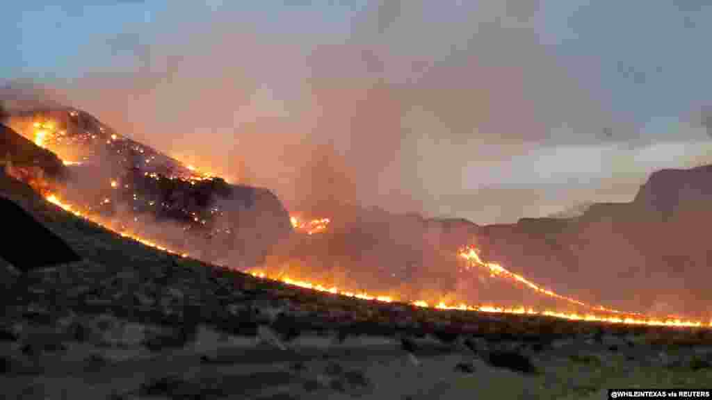 Flames are seen on side of highway after a bushfire broke out, near St. George, Arizona, July 12, 2021, in this still image obtained from a social media video. (Twitter@WHILEINTEXAS)