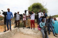 FILE - Somali journalists are seen during a stake-out on the outskirts of Mogadishu, Somalia, July 25, 2019.