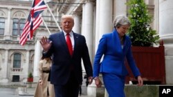 Britain's Prime Minister Theresa May and President Donald Trump walk through the Quadrangle of the Foreign Office for a joint press conference in central London, June 4, 2019.