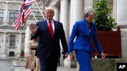 Britain's Prime Minister Theresa May and President Donald Trump walk through the Quadrangle of the Foreign Office for a joint press conference in central London, June 4, 2019.