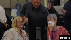 A neutral worker and a Republican and Democratic representative adjudicate ballots cast in the US midterm elections at the Maricopa County Tabulation and Election Center in Phoenix, Arizona, Nov. 9, 2022.