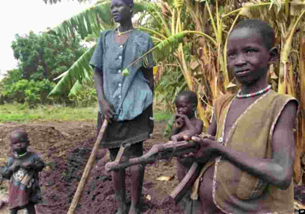 Anak-anak bermain dengan senapan otomatis rusak yang ditemukan terkubur di tanah di Nyal, Unity State, Sudan Selatan. (AP/Josphat Kasire)