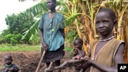 In this photo taken Tuesday, May 6, 2014 and made available Tuesday, May 13, 2014, John Kawai Lam, 8, right, plays with a non-functioning automatic rifle that he found buried in the soil when he and his mother Tabitha Nyanyun Ruach, 38, center, were culti