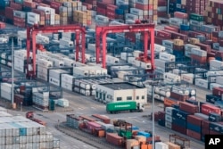 FILE - A cargo truck drives amid stacked shipping containers at the Yangshan port in Shanghai, China, March 29, 2018.