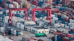 FILE - A cargo truck drives amid stacked shipping containers at the Yangshan port in Shanghai, China, March 29, 2018.