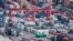 FILE - A cargo truck drives amid stacked shipping containers at the Yangshan port in Shanghai, China, March 29, 2018.