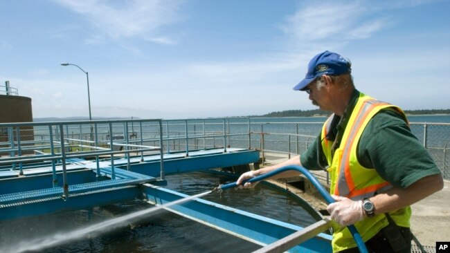 FILE - Robert Newman hoses off a portion of sewage treatment Plant No. 2 in Coos Bay, Oregon, May 13, 2010.