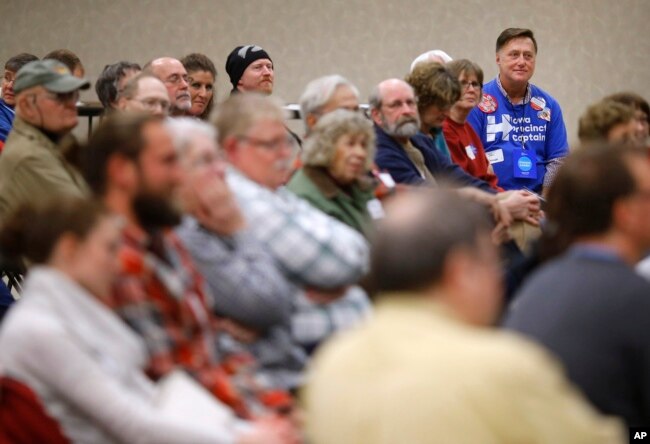 FILE - John Grause, top right, precinct captain for Democratic presidential candidate Hillary Clinton, sits with voters during a Democratic party caucus in Nevada, Iowa, Feb. 1, 2016.