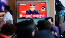 FILE - People watch a TV screen showing an image of North Korean leader Kim Jong Un during a news program at the Seoul Railway Station in Seoul, South Korea, April 21, 2018. The signs read: "North Korea says it has suspended nuclear tests."