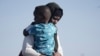 FILE - A Sudanese evacuee carries her son as they disembark from the USNS Brunswick at Jeddah port, Saudi Arabia, May 4, 2023.