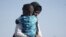 FILE - A Sudanese evacuee carries her son as they disembark from the USNS Brunswick at Jeddah port, Saudi Arabia, May 4, 2023.