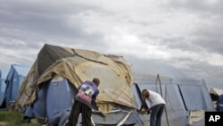 Men try to tie down their tent, which serves as their home, as Tropical Storm Emily idles just south of the slum area of Cite Soleil, Haiti, August 4, 2011