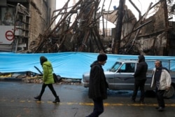 People walk past buildings that were burned during recent protests, in Shahriar, Iran, some 40 kilometers (25 miles) southwest of the capital, Tehran, Nov. 20, 2019.