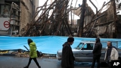 People walk past buildings which burned during protests that followed the authorities' decision to raise gasoline prices, in the city of Karaj, west of Tehran, Nov 18, 2019.