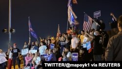 Supporters of U.S. President Donald Trump, hold American flags and placards as they pose during a "Stop the Steal" protest following the 2020 U.S. presidential election in Las Vegas, Nov. 4, 2020.