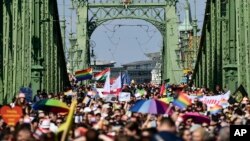 Para peserta pawai hak-hak LGTBQ, Pride Parade, berjalan melintasi Szabadsag atau Jembatan Kebebasan di atas Sungai Danube di pusat kota Budapest, Hongaria, Sabtu, 24 Juli 2021. (Foto: AP/Anna Szilagyi)