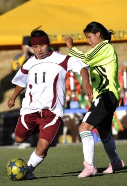 Diana Quispe (Kiri), dari tim sepak bola pasar Rodriguez, bersaing memperebutkan bola dengan Mariana Calle, dari pasar Los Pinos, selama pertandingan final antar pasar, di La Paz pada 27 Juli 2012. 32 tim wanita pribumi, pemegang kios dari pasar populer,