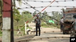 A Myanmar police officer stands watch as journalists arrive in the village of Shwe Zar, in the northern part of Myanmar's Rakhine state, Sept. 6, 2017.