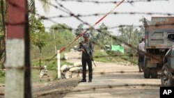 FILE - A Myanmar police officer stands watch as journalists arrive in the village of Shwe Zar, in the northern part of Myanmar's Rakhine state, Sept. 6, 2017.