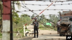 FILE - A Myanmar police officer stands watch as journalists arrive in the village of Shwe Zar, in the northern part of Myanmar's Rakhine state, Sept. 6, 2017.