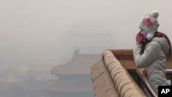 A woman adjusts her mask during a heavily polluted day in Beijing Tuesday, Dec. 22, 2015.