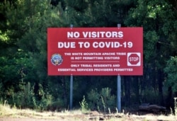 In this Thursday, June 25, 2020 photo provided by C.M. Clay, a sign alerts motorists that visitors are not allowed on the Fort Apache Indian Reservation in eastern Arizona. The reservation, home to…