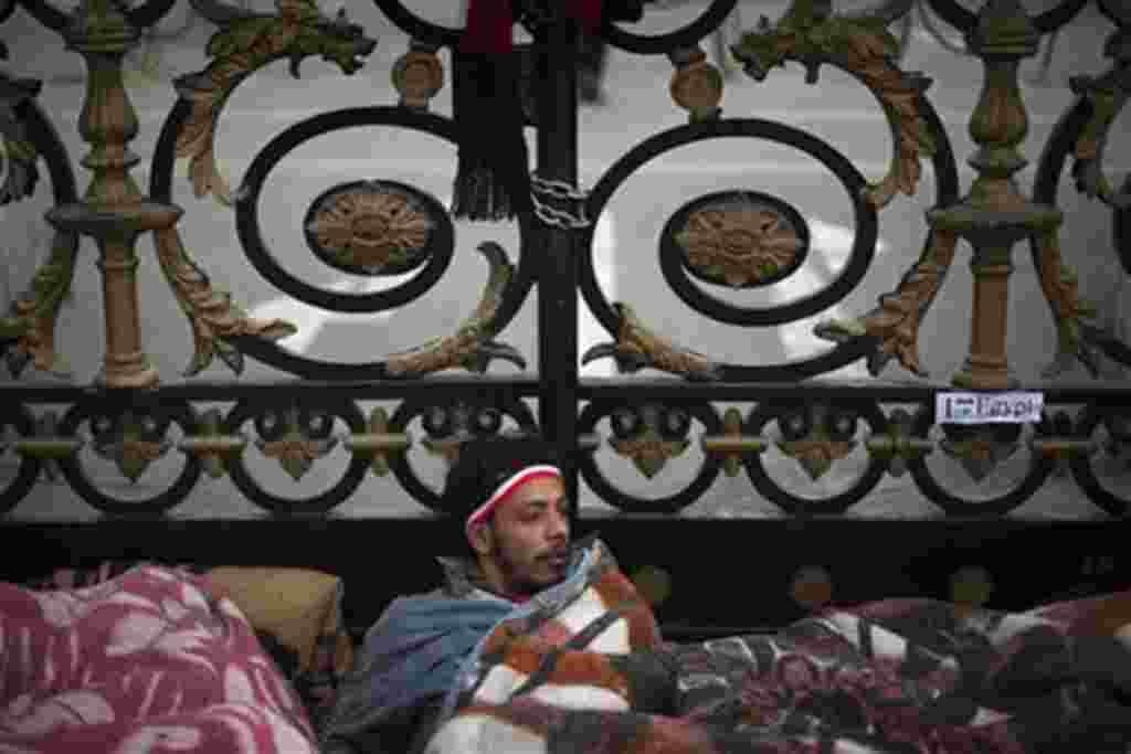 An anti-government protester wakes up after spending the night in front of the main gate of the Egyptian Parliament in Cairo, February 10, 2011