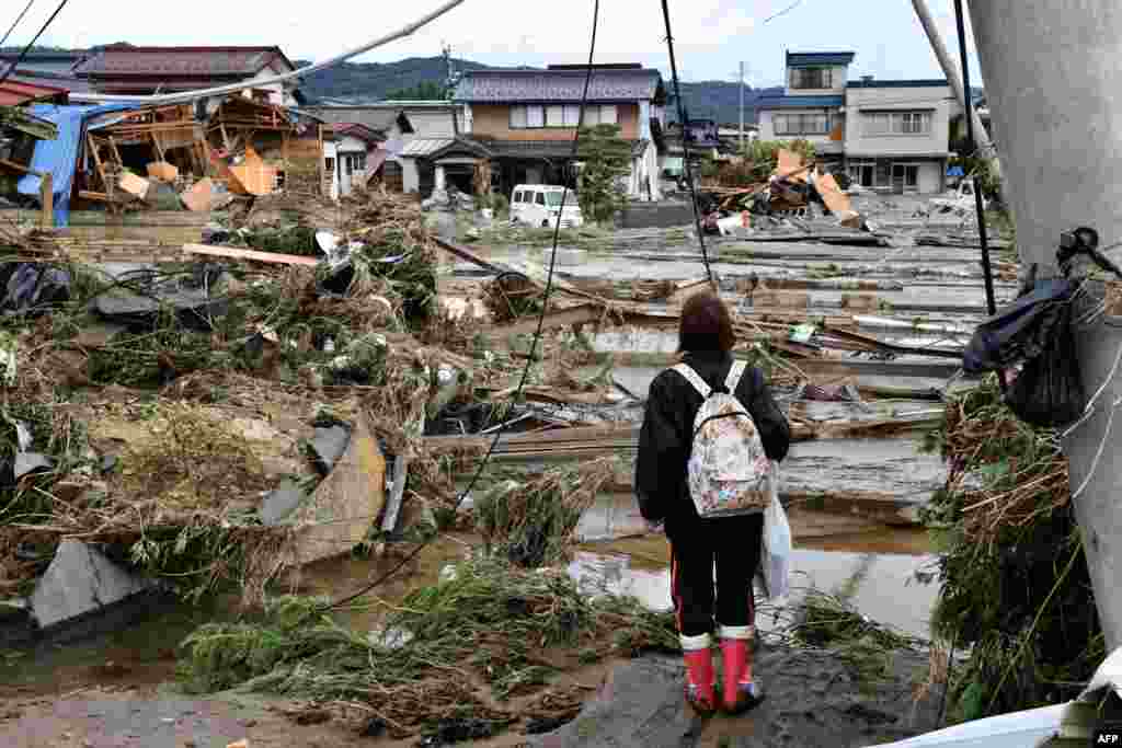 A woman looks at flood-damaged homes in Nagano, after Typhoon Hagibis hit Japan, unleashing high winds, torrential rain and triggering landslides and catastrophic flooding.