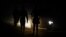 FILE: Locals are illuminated by car lights as they walk on the dark streets during frequent power outages from South African utility Eskom, caused by its aging coal-fired plants, at Lawley Township, South Africa 7.13.2022