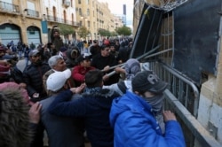 Demonstrators attempt to remove a barrier fence during a protest against the newly formed government in Beirut, Lebanon, Jan. 22, 2020.