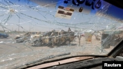 An Iraqi security vehicle is pictured through a shattered windshield of a vehicle damaged at the site of car bomb attack in Rashidiya a district north of Baghdad, Iraq, July 12, 2016.