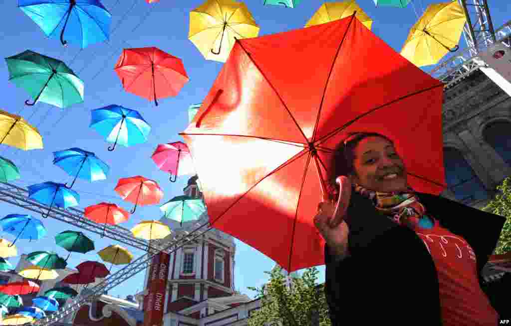 A woman carries an umbrella as she walks along &quot;The alley of flying umbrellas&quot; art installation in central St. Petersburg, Russia.