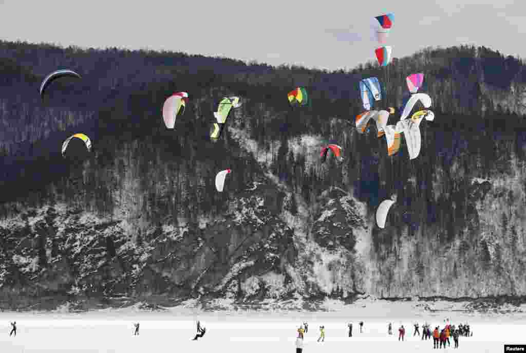 Kite boarders and kite skiers compete during an amateur regional championship on the frozen Yenisei River in the taiga district, south of the Russian Siberian city of Krasnoyarsk. 