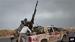 Libyan rebels jump onto back of their vehicle as they leave Ras Lanouf in central Libya after Gadhafi's forces drove rebels out of Bin Jawwad, a hamlet east of Sirte, March 29, 2011