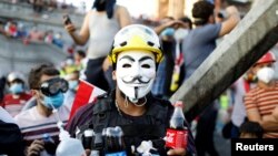 An Iraqi demonstrator carries bottles of soda used to neutralize tear gas during an anti-government protest in Baghdad, Iraq, Nov. 1, 2019. 