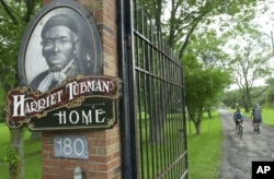 FILE - Children ride their bikes down the drive passing the Harriet Tubman Home in Auburn, N.Y. The home of the abolitionist is along a trail of memorials and museums from New England south to Washington, D.C., that extol women's achievements in molding t